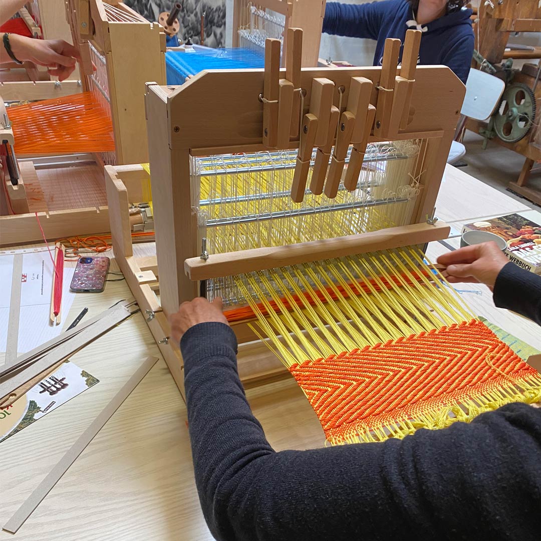 Kursteilnehmerinnen an Schaftwebstühlen beim Ausprobieren verschiedener Bindungen und Garne
